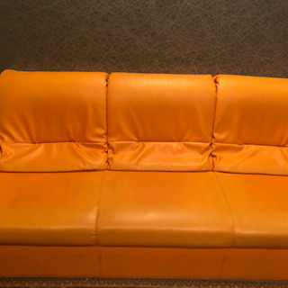 オレンジ色の３人掛けソファー