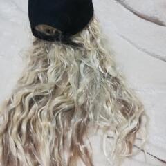 黒い帽子に金髪ロングが付いているウイッグ